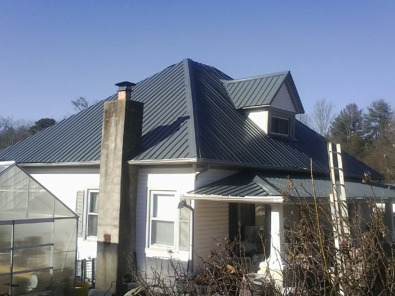 Dark blue standing seam metal roof on a white farmhouse with dormer — Slate & Tile Roof Repair by Roofing Brothers in Waynesfield