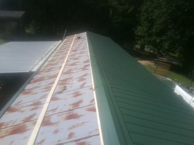 Old rusted panels beside newly installed green metal roofing — Wind Damage Roof Repair by Roofing Brothers in Waynesfield