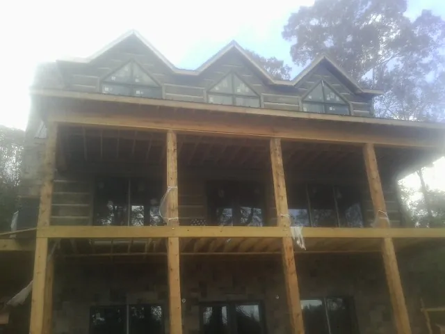 Dormers and porch framing on a large log home under construction — Roof Coating work by our crew in Waynesfield