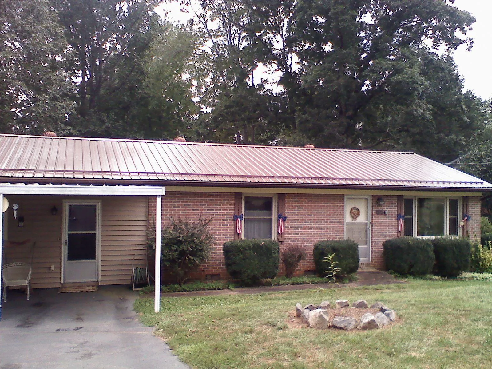 Bronze metal roof and carport on a brick ranch home — Roof Repair work by our crew in Waynesfield