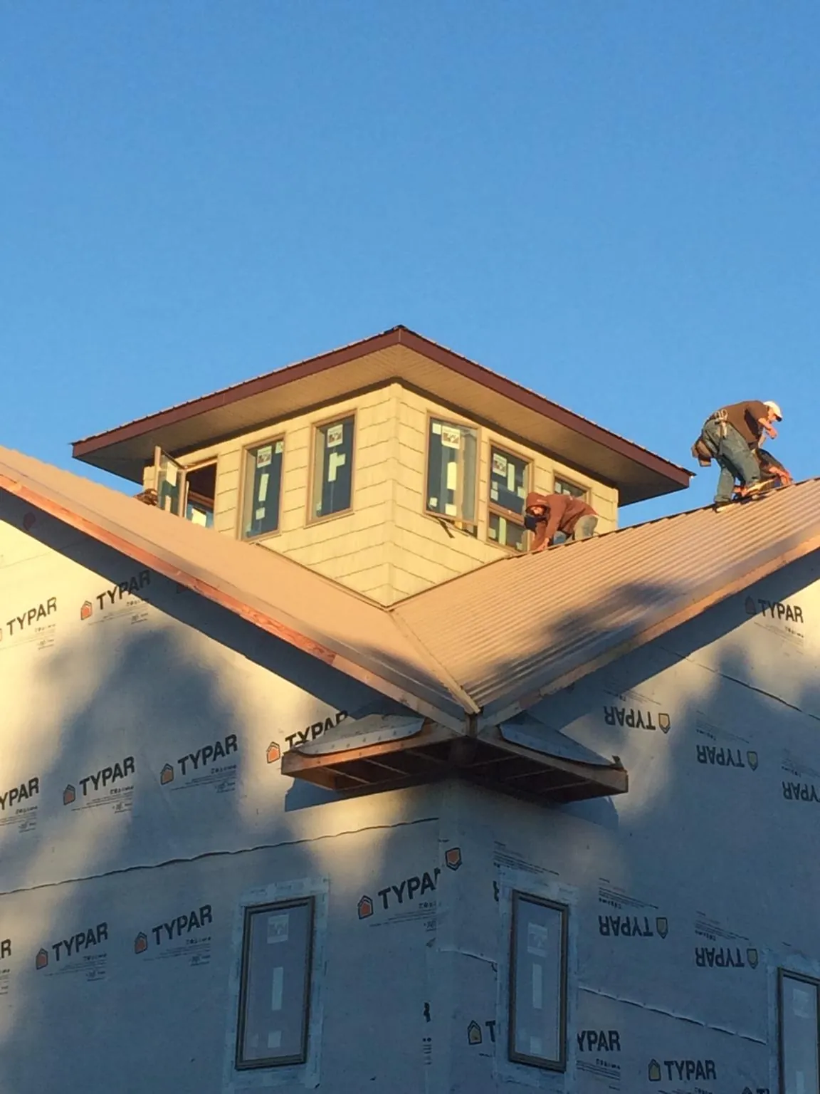 Roofers working around a rooftop cupola on a new metal roof at sunset — Roof Waterproofing in Waynesfield by Roofing Brothers